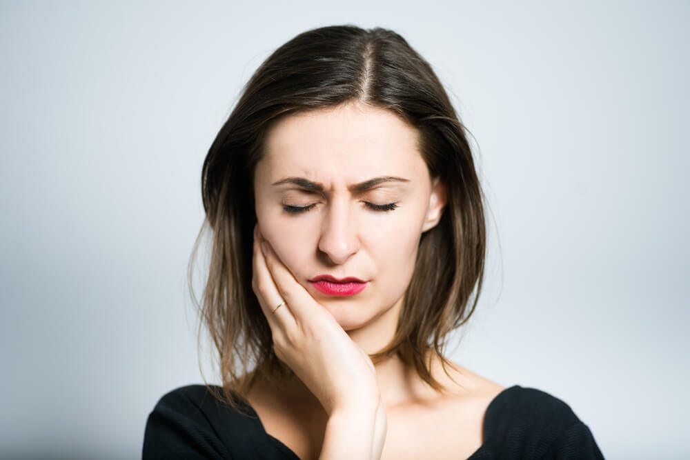 Woman holding her mouth in dental pain