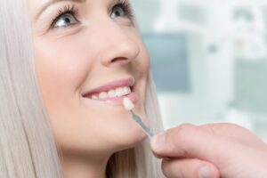 Dental veneer held up to a woman's teeth