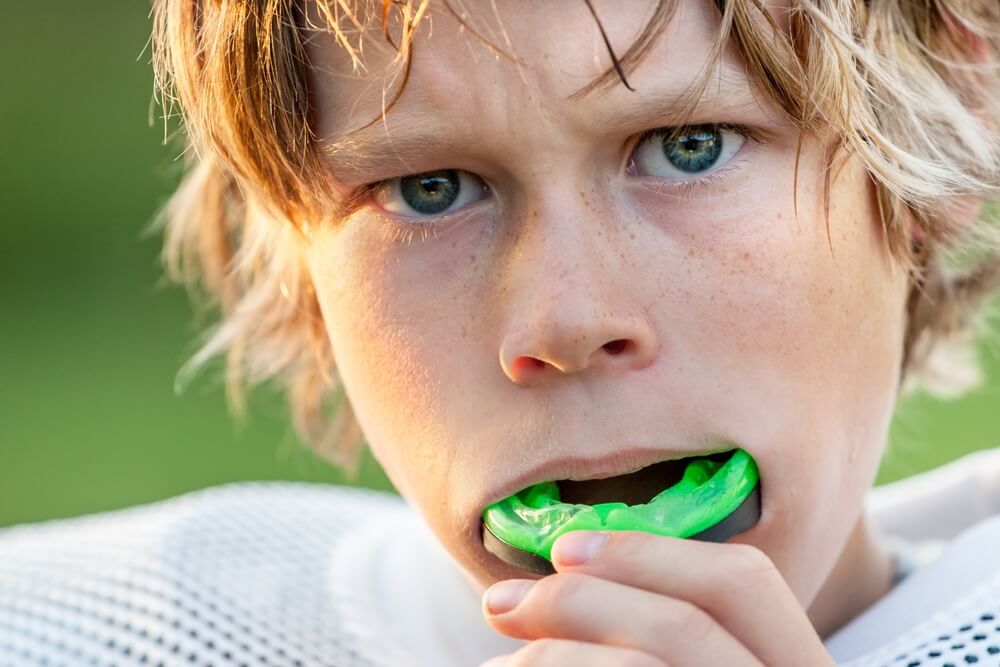 Young football player putting in a mouthguard