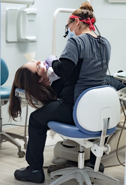 One of our dental assistants applying dental treatment to a woman lying in the dentist's chair